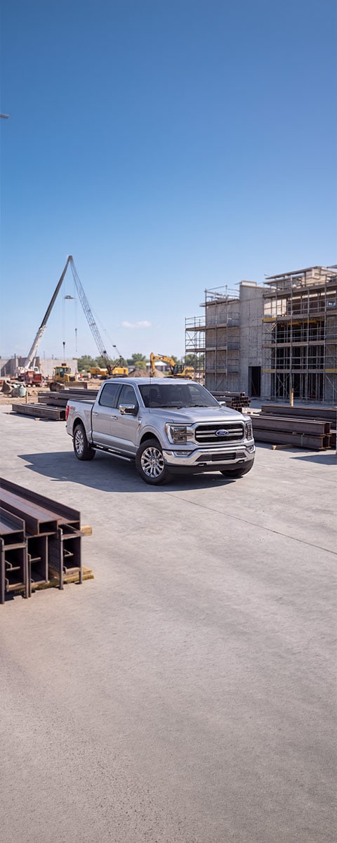 Nueva Ford F-150 plateada en vista frontal de tres cuartos en una zona de construcción.