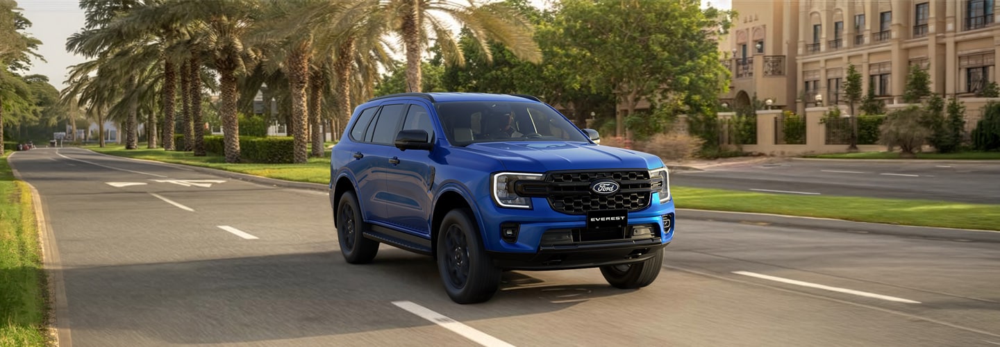 Ford Everest Sport azul en movimiento sobre una avenida rodeada de palmeras.