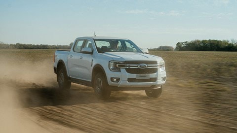 Ford Ranger blanca en movimiento sobre un camino de tierra, levantando polvo.