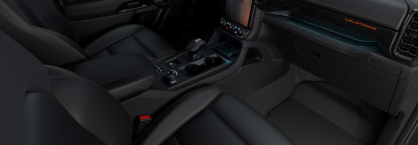 Interior de la Ford Ranger Wildtrak con asientos delanteros, consola central y detalles en color naranja.